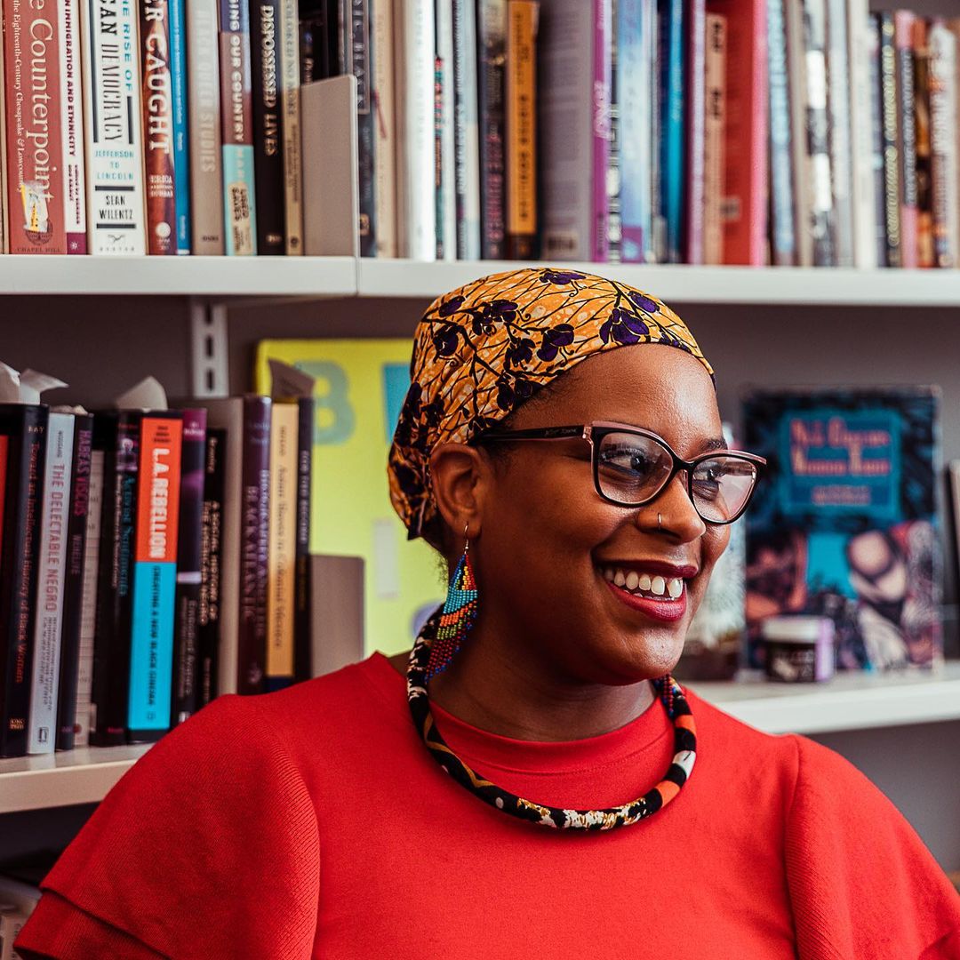 JMJ in a yellow headwrap smiling in her office